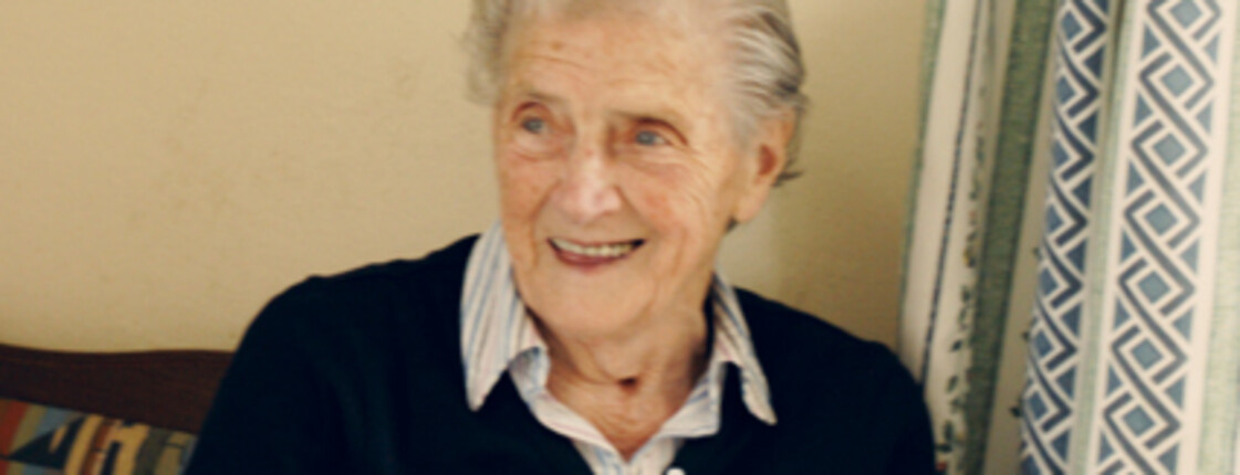 An elderly woman with a friendly smile in her home